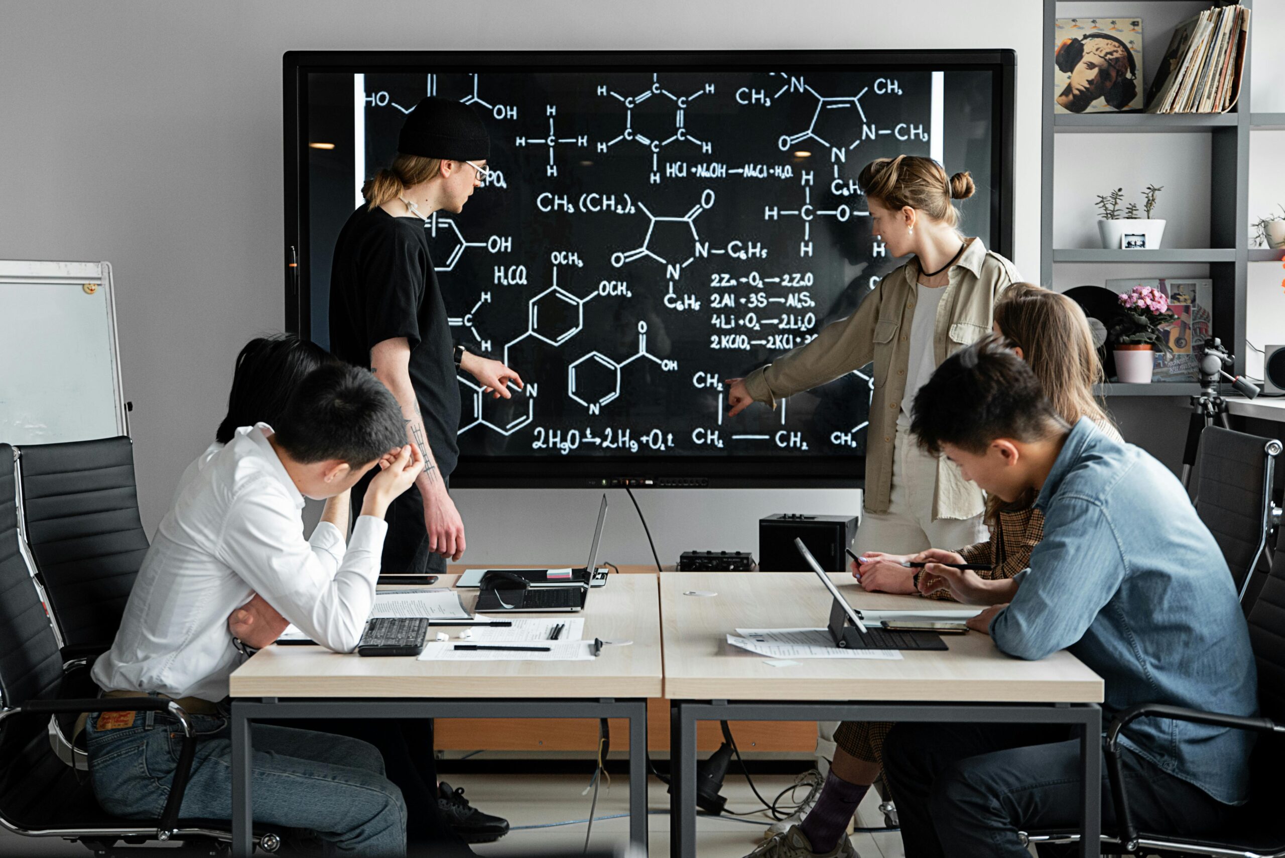 Group of young professionals collaborating on chemical formulas in a modern office setting.